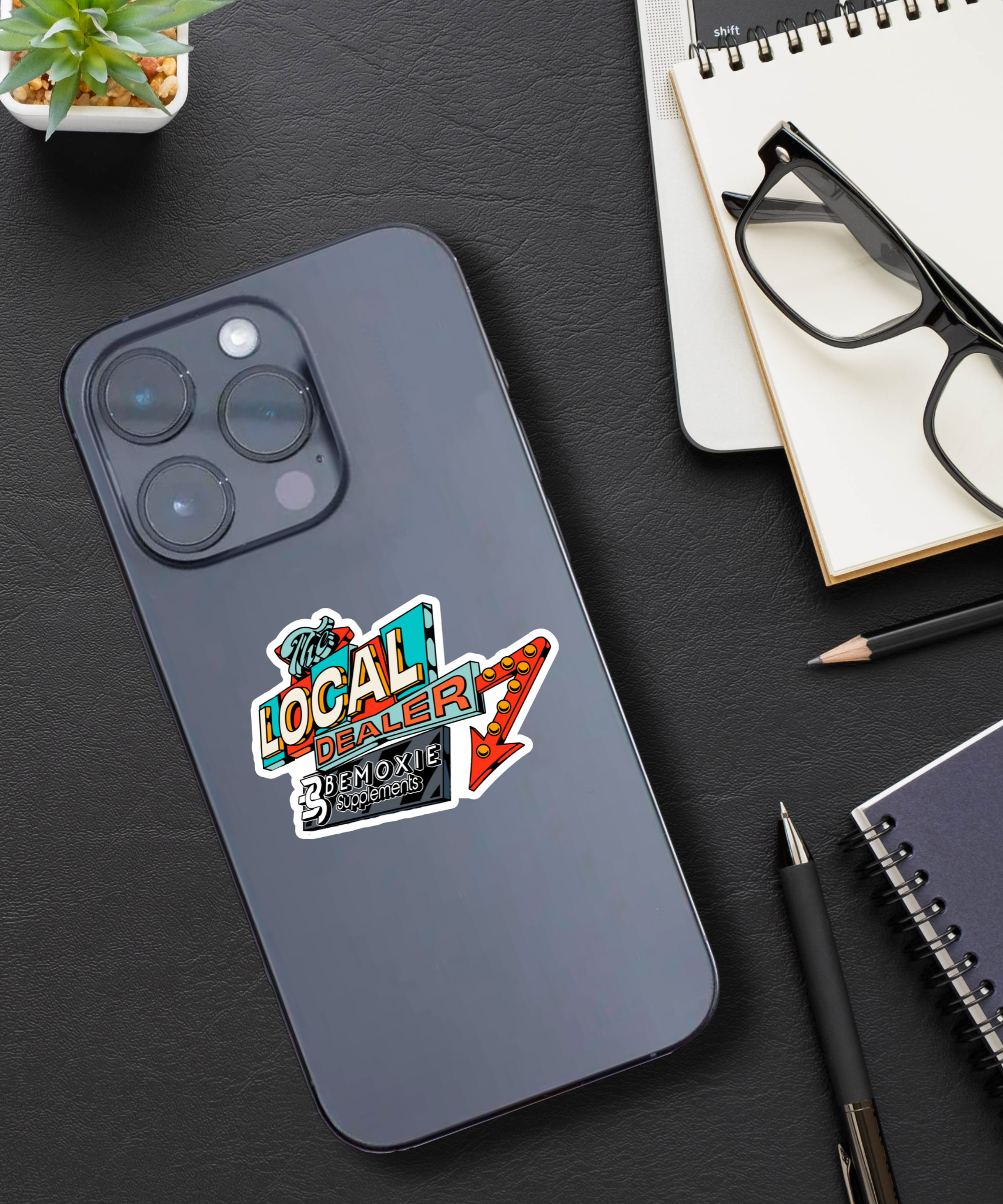 Phone case with colorful graphic design on a dark surface with office items.